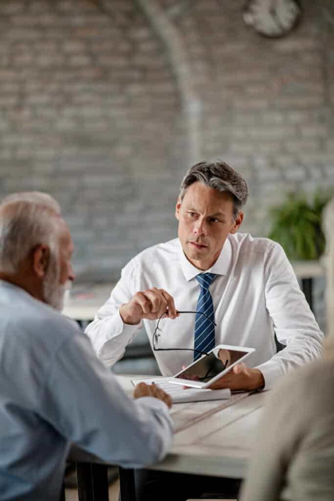 insurance agent communicating with senior clients while showing something touchpad during meeting office Home